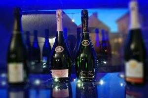 Photographie, intérieur. 2 bouteilles de champagne de forme particulière (plus bombée) sont présentées. Textes étiquettes : Prestige ; Ephémère rosé. Champagne Didier Lapie, Viticulteur à Vaudemange.